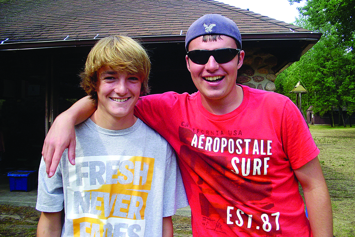 Childcare Programs YMCA staff member reading a book to two young boys while seated in a colorful activity room.