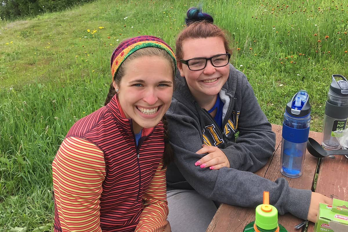 Childcare Programs YMCA staff member reading a book to two young boys while seated in a colorful activity room.