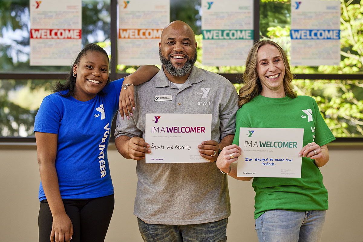 Two Y staff and a Y volunteer smile and holding