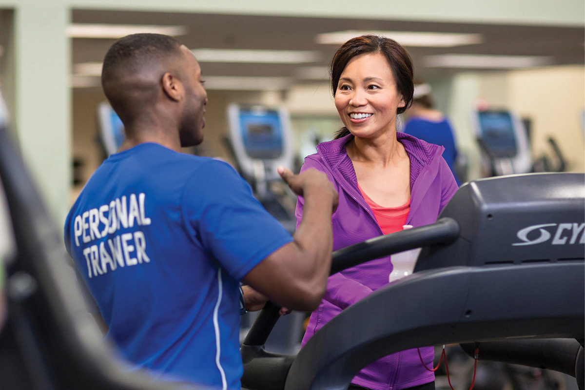 Childcare Programs YMCA staff member reading a book to two young boys while seated in a colorful activity room.