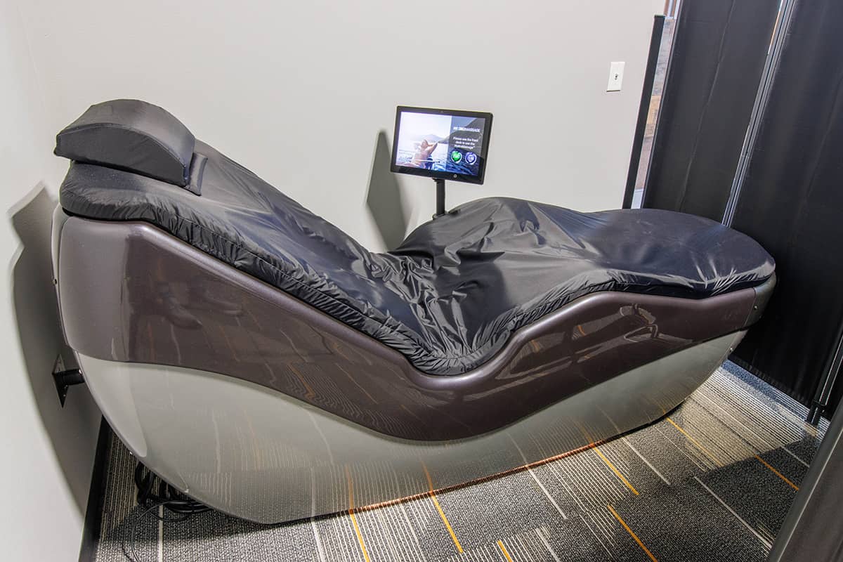 Childcare Programs YMCA staff member reading a book to two young boys while seated in a colorful activity room.