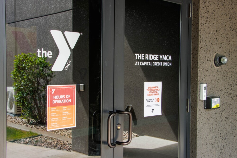 Childcare Programs YMCA staff member reading a book to two young boys while seated in a colorful activity room.